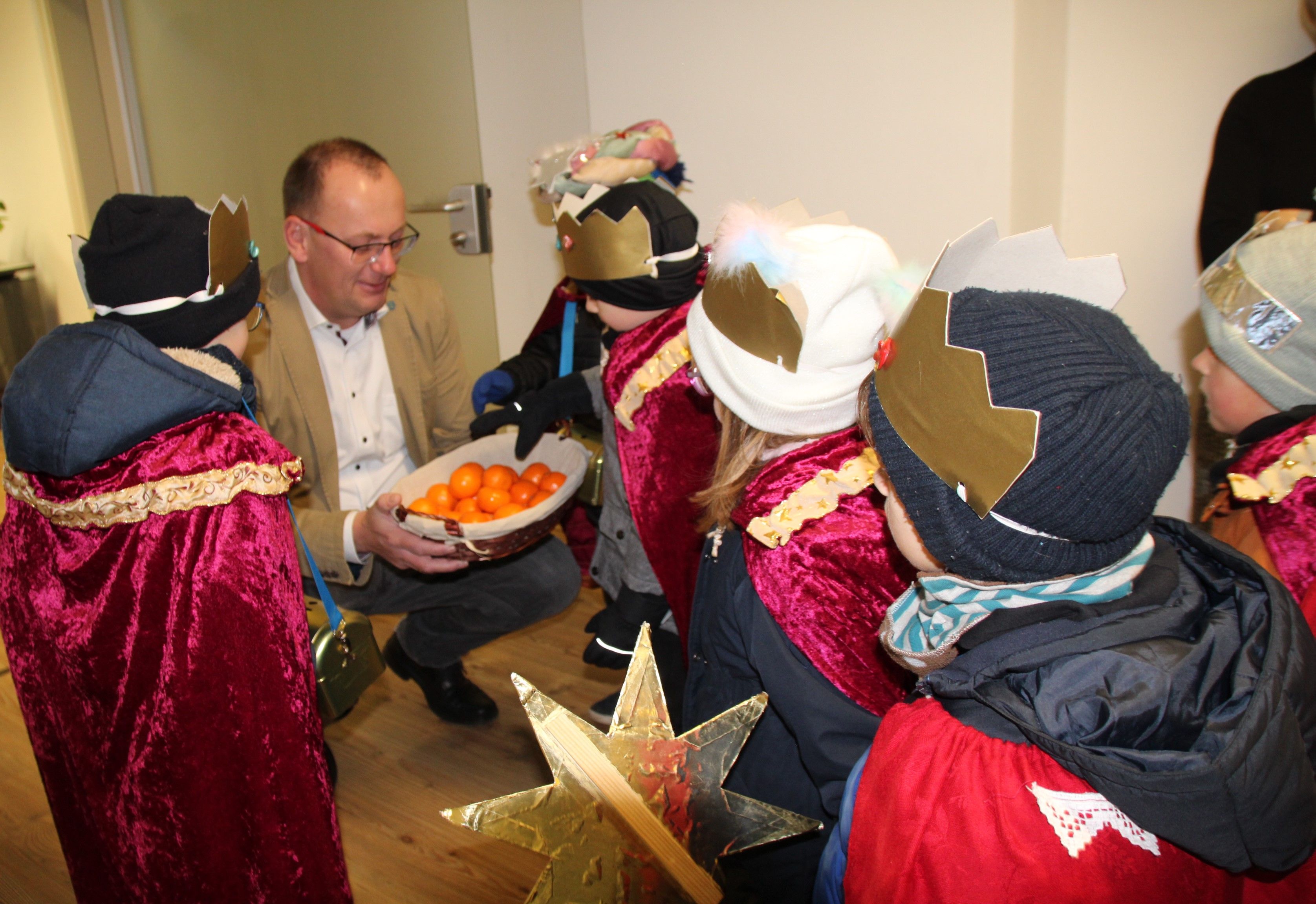 Oberbürgermeister Sven Strauß verteilt an die Kinder Mandarinen.